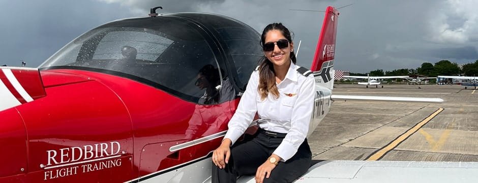Female student pilot posing with an Redbird aircraft